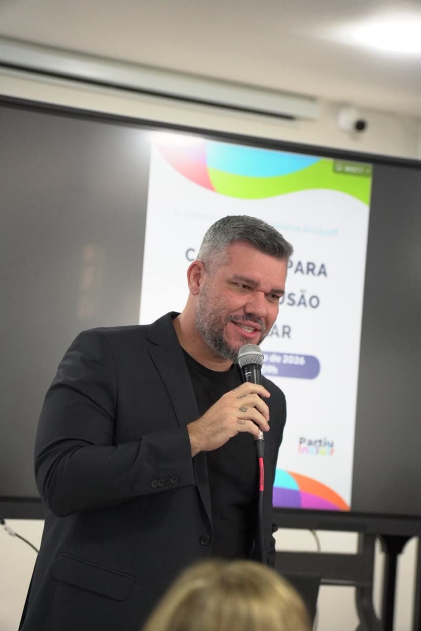 Paulo Pereira discursando com microfone em evento sobre inclusão